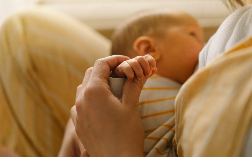 a newborn aby wrapped in swaddle and a mom nursing her baby