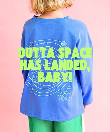 Child wearing a blue shirt with 'Outta Space Has Landed, Baby!' text on a pink background